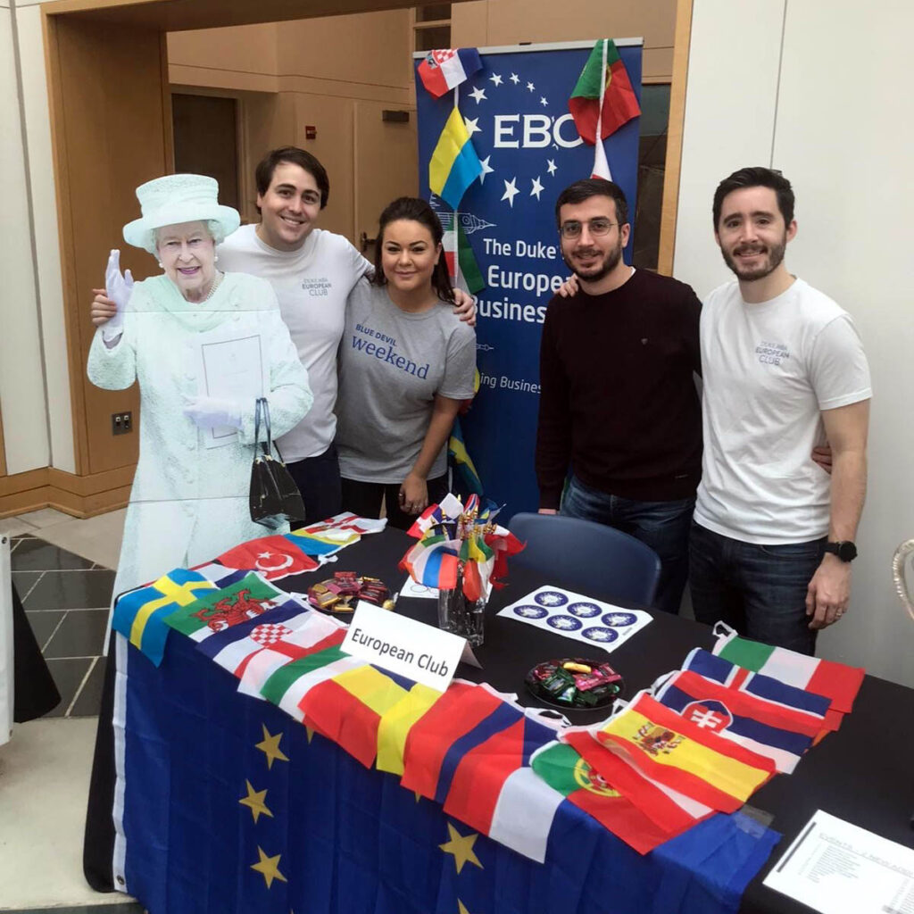 four students and a life-sized cut out of Queen Elizabeth II stationed at an info booth; advice for European applicants