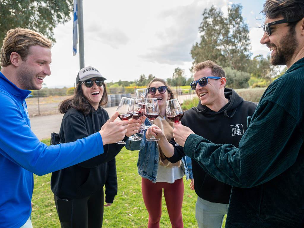 A group of students toasting with a glass of red wine