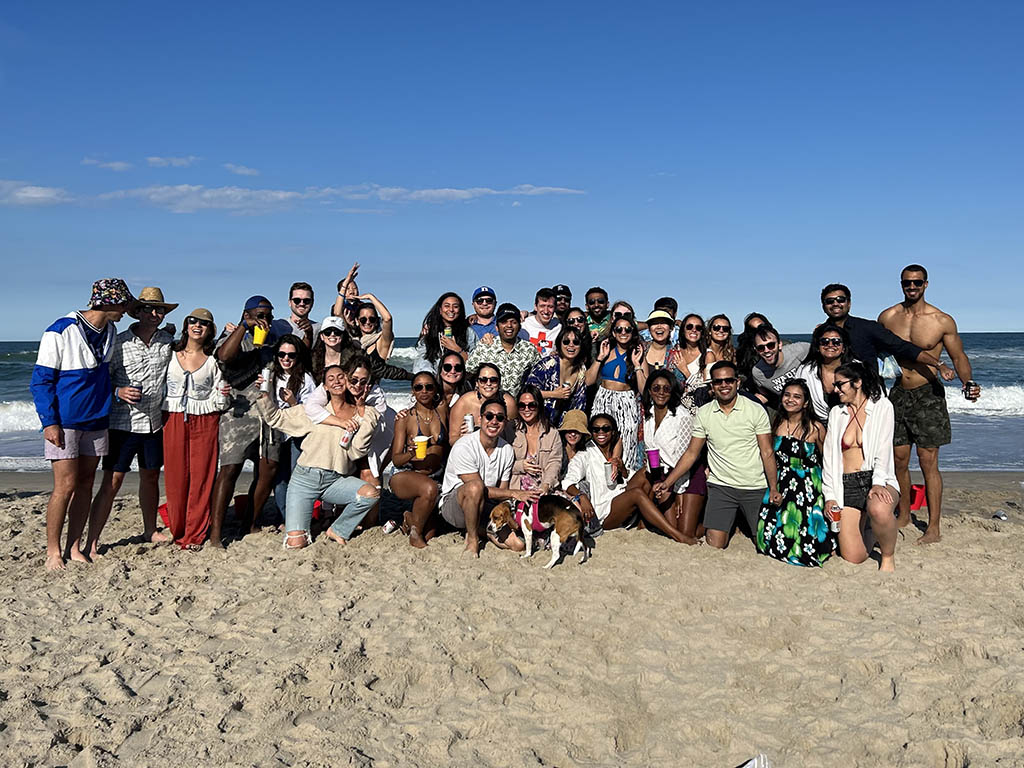 dozens of people in group photo on the beach with the ocean in the background