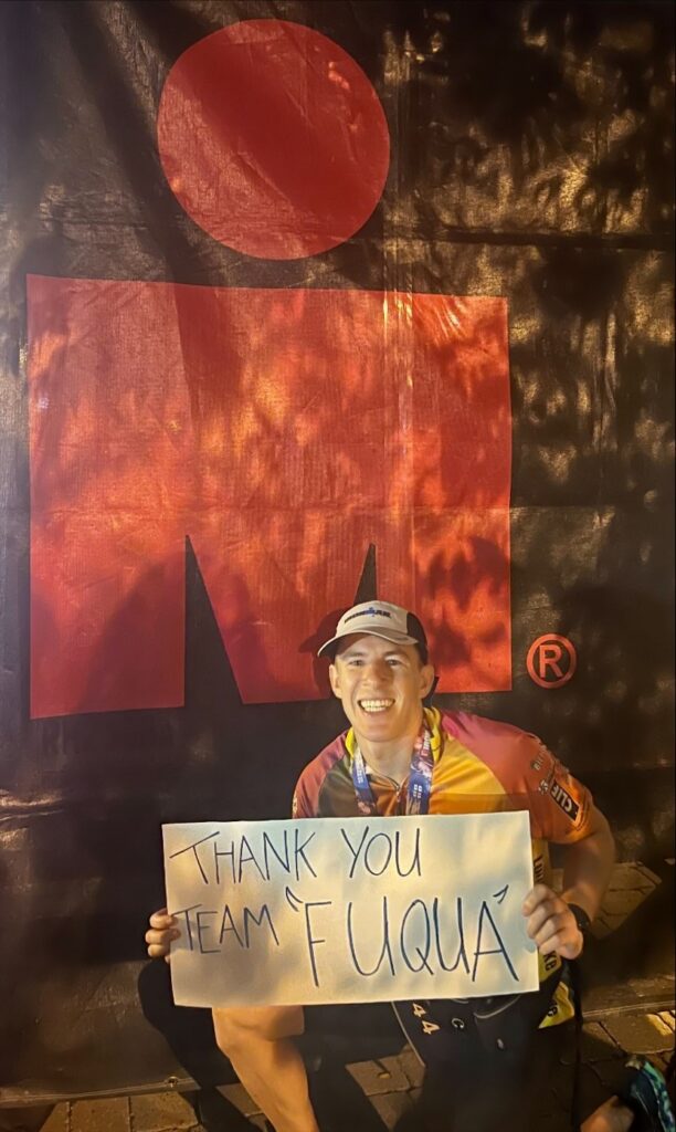 Daytime MBA alumnus Danny Auerbach poses with sign that reads "thank you team Fuqua" after finishing his first Ironman competition
