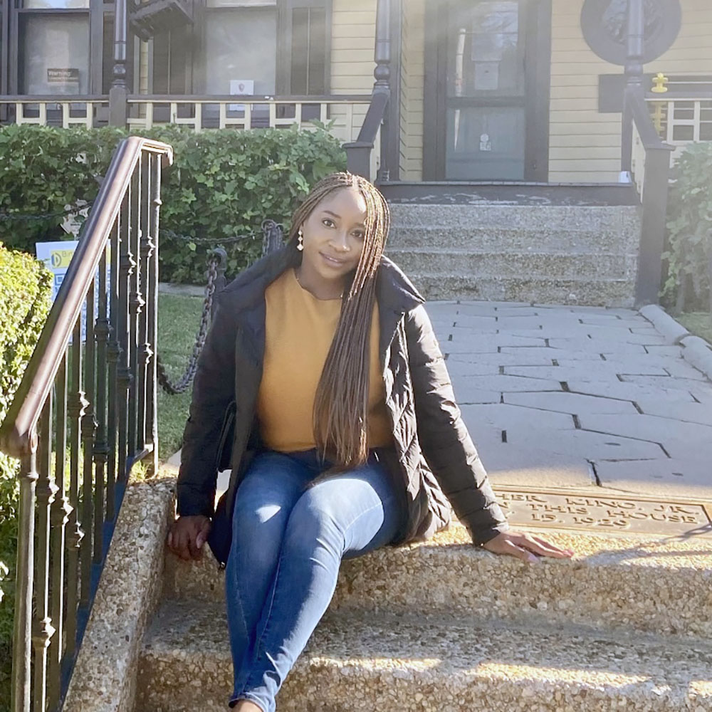 Queen Nwokonneya sitting on stairs in front of a home