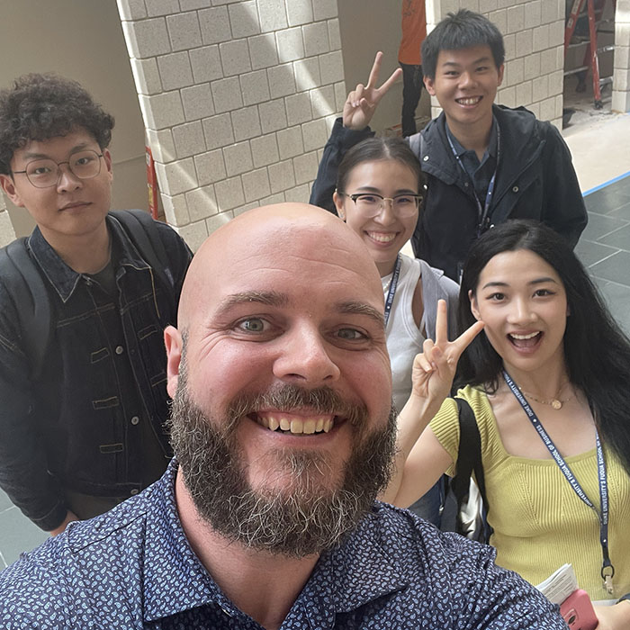 Four Fuqua students and a staff member take a selfie in the mallway 