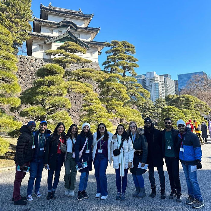 Padmini Muralidhar and about 10 of her classmates standing in front of Japanese architecture while on the Tokyo MBA trek during a break from the Daytime MBA program