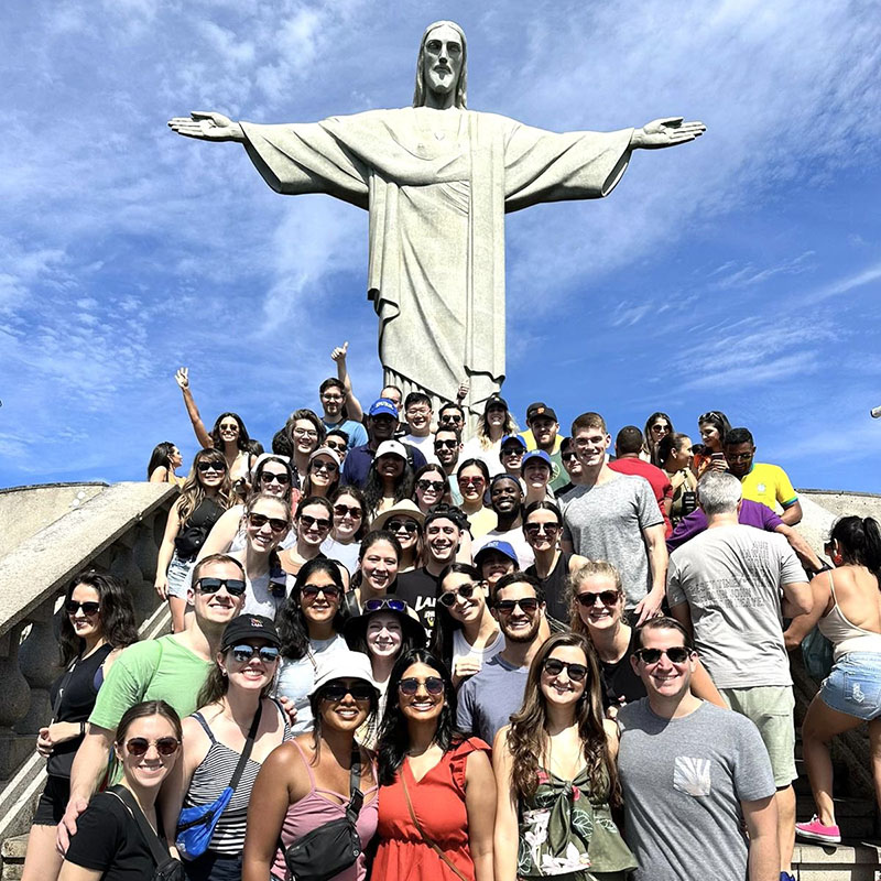 Monika Palabindela and several of her Daytime MBA classmates with friends and partners. They are standing in a group in front of the Christ the Redeemer statue in Rio de Janeiro, Brazil