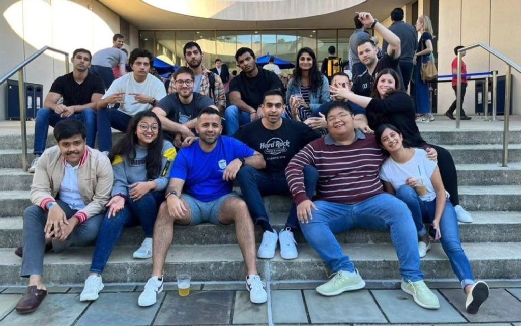 A group of students sit together on the stairs in front of the Fox Center entrance at Duke University's Fuqua School of Business