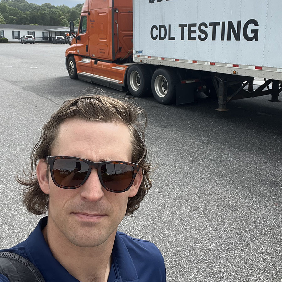 Nathan Schwartzbauer in front of a semitruck reading "CDL testing"