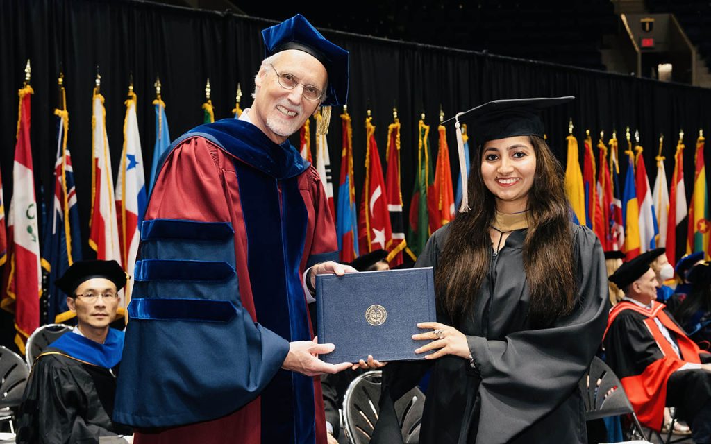 Ayushi Saxena accepts her diploma from then-Dean Bill Boulding