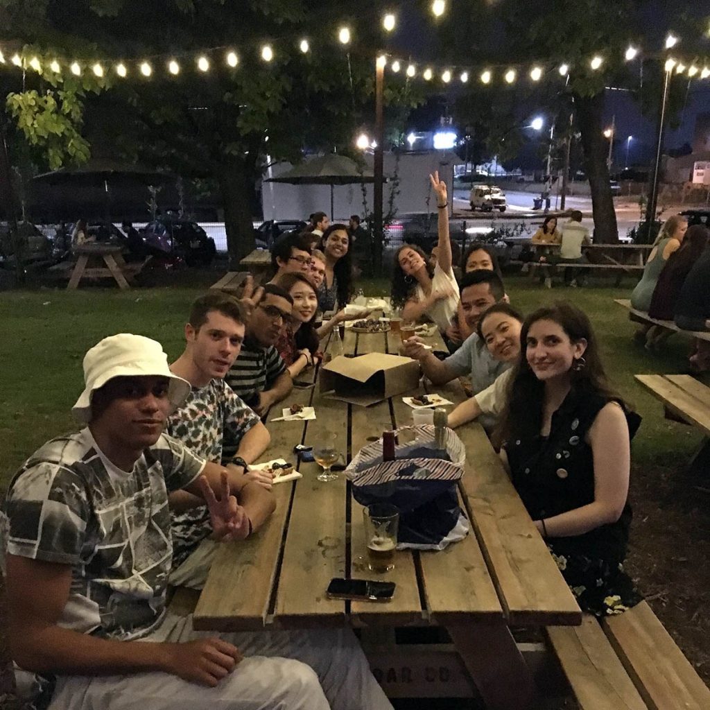 a dozen students around a long picnic table outside; nightlife in Durham