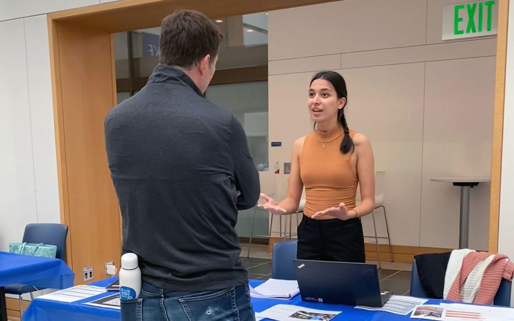 Mehak Bishnoi, a student in the MMS program at Duke University's Fuqua School of Business, speaking at an event table in the Fox Center