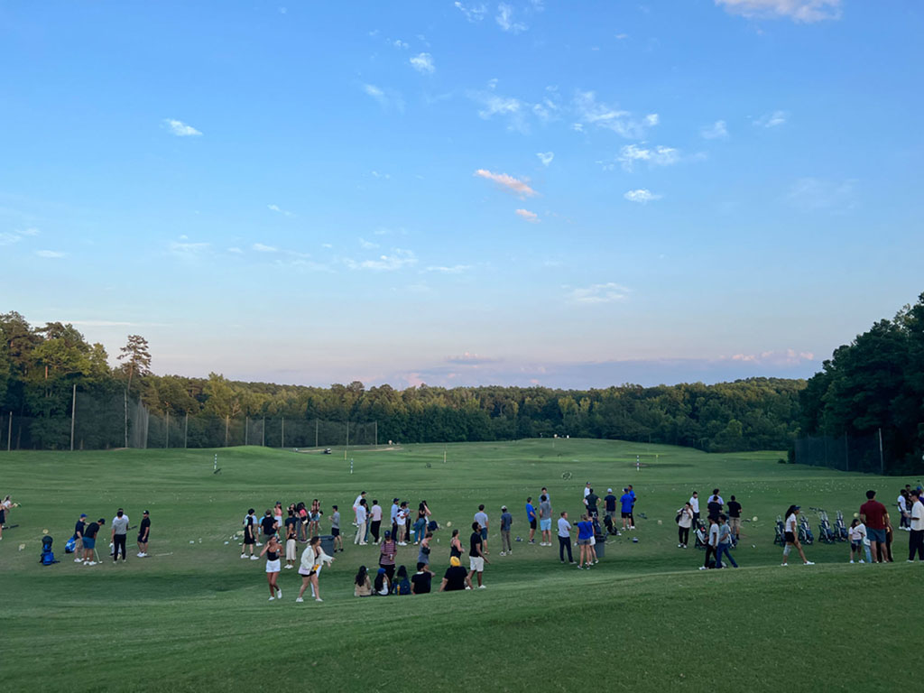 Dozens of people practice at the driving range at the Washington Duke course