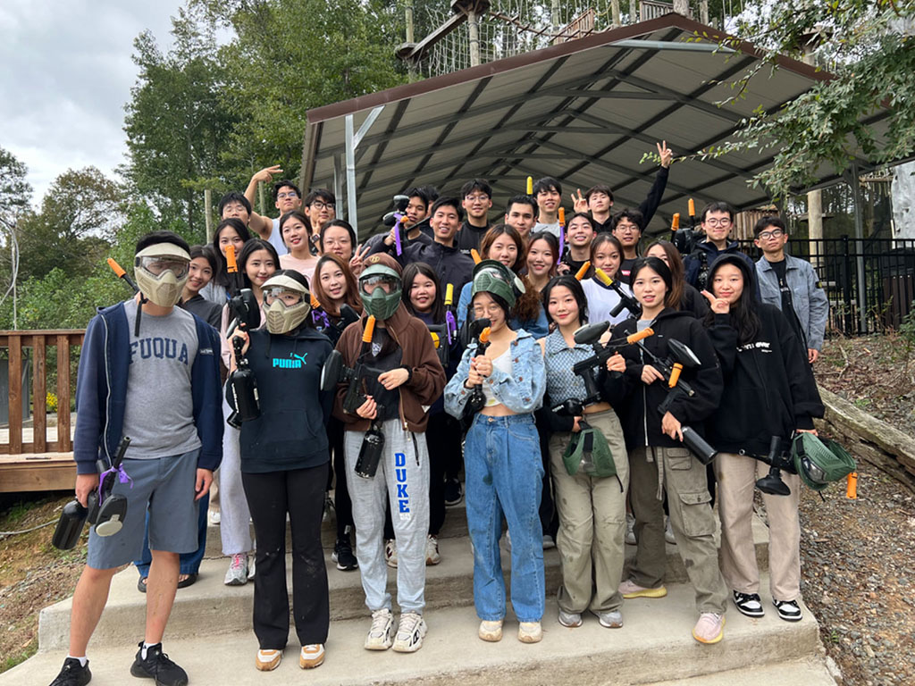 Hantao Gan, an MMS: DKU student, with a large group of his classmates dressed in paintball battle attire at the paintball facility