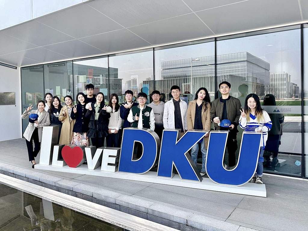 Students in the MMS: DKU program gather behind a "love DKU" sign on the DKU campus