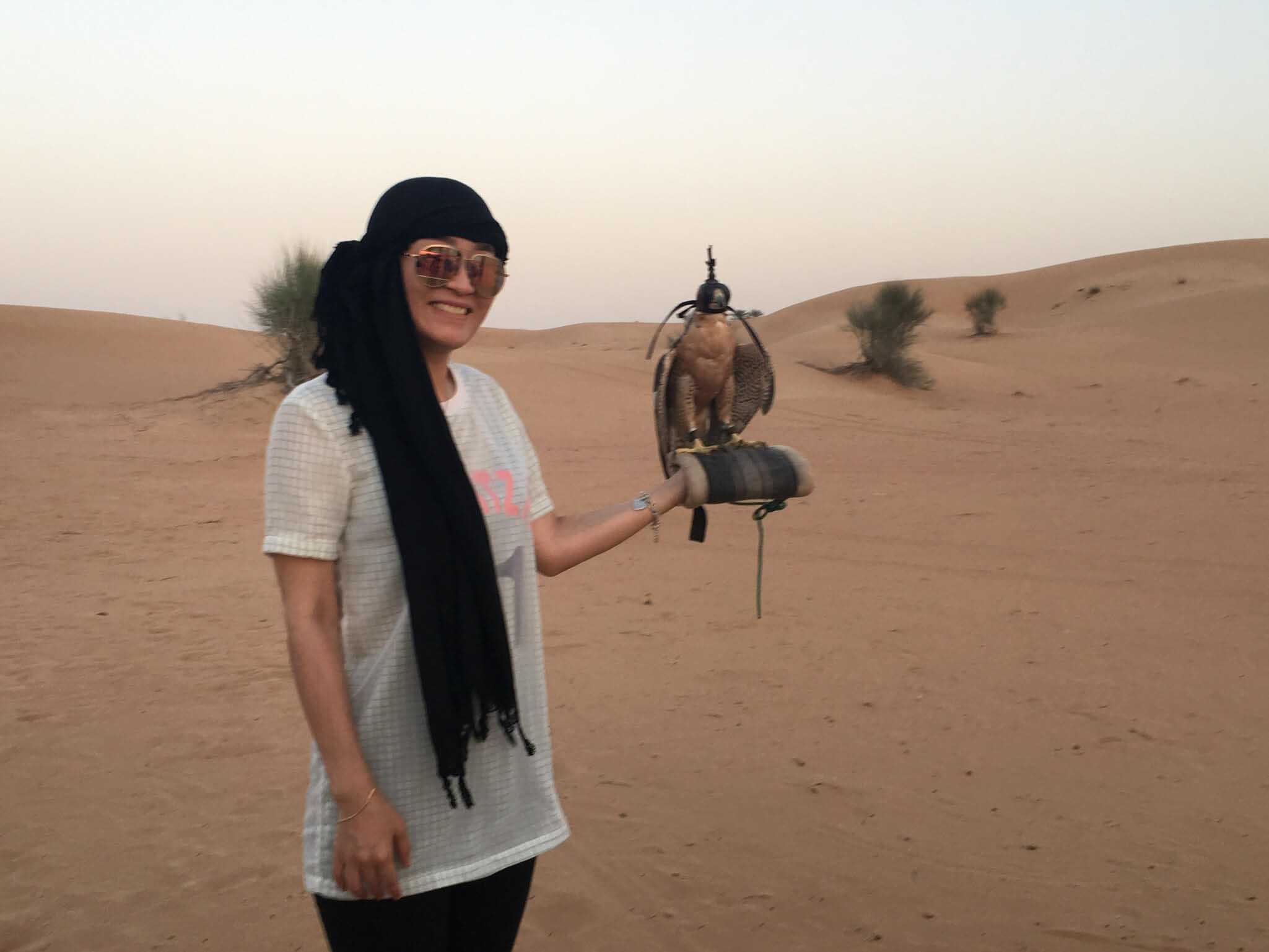 Student holding a bird in a Dubai desert