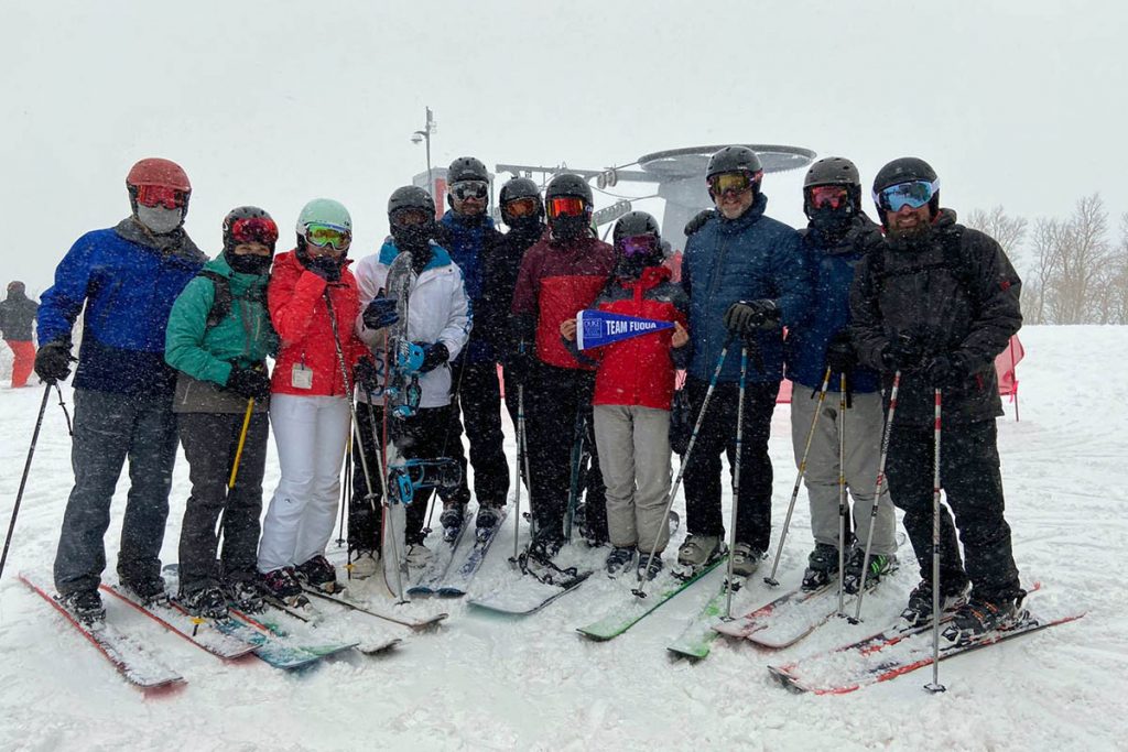 a dozen classmates on a ski slope posting with a Team Fuqua sign; some of the most rewarding experiences of my life
