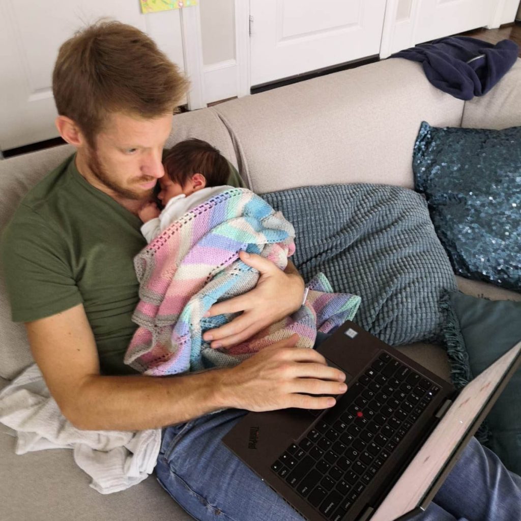 Alexander with Cleo sleeping on his chest while he works on his laptop; work-life balance