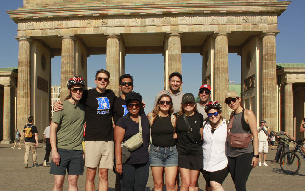 9 members of the Global Executive MBA Class of 2024 posing for a photo in Berlin, some are wearing bike helmets