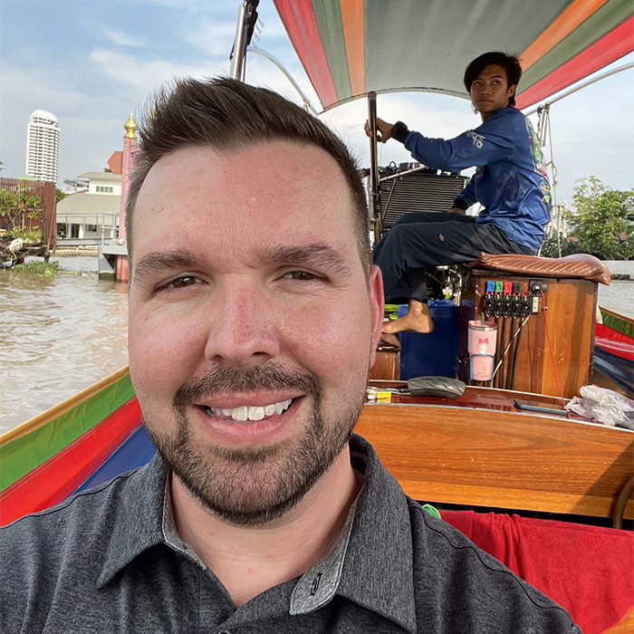 Matt Engle on a boat in Thailand, the boat operator is just behind him