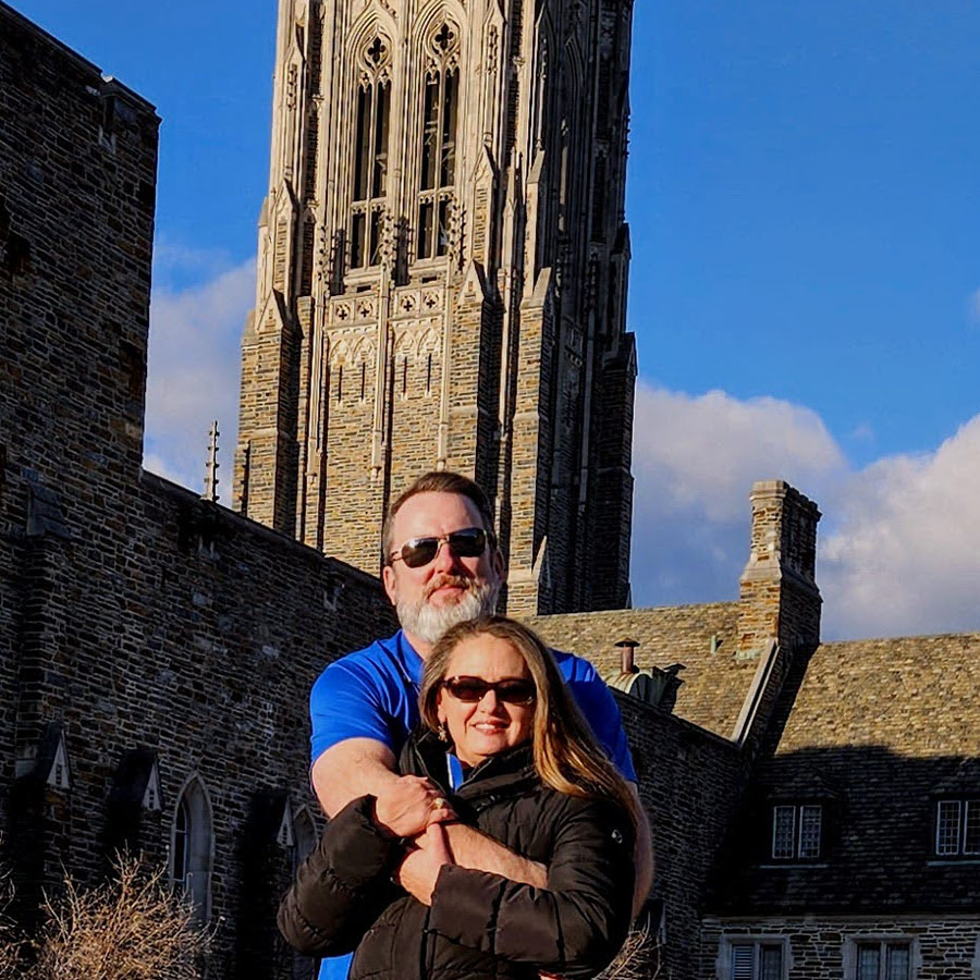 Rob Saylor hugs his wife from behind in the quad near Duke Chapel