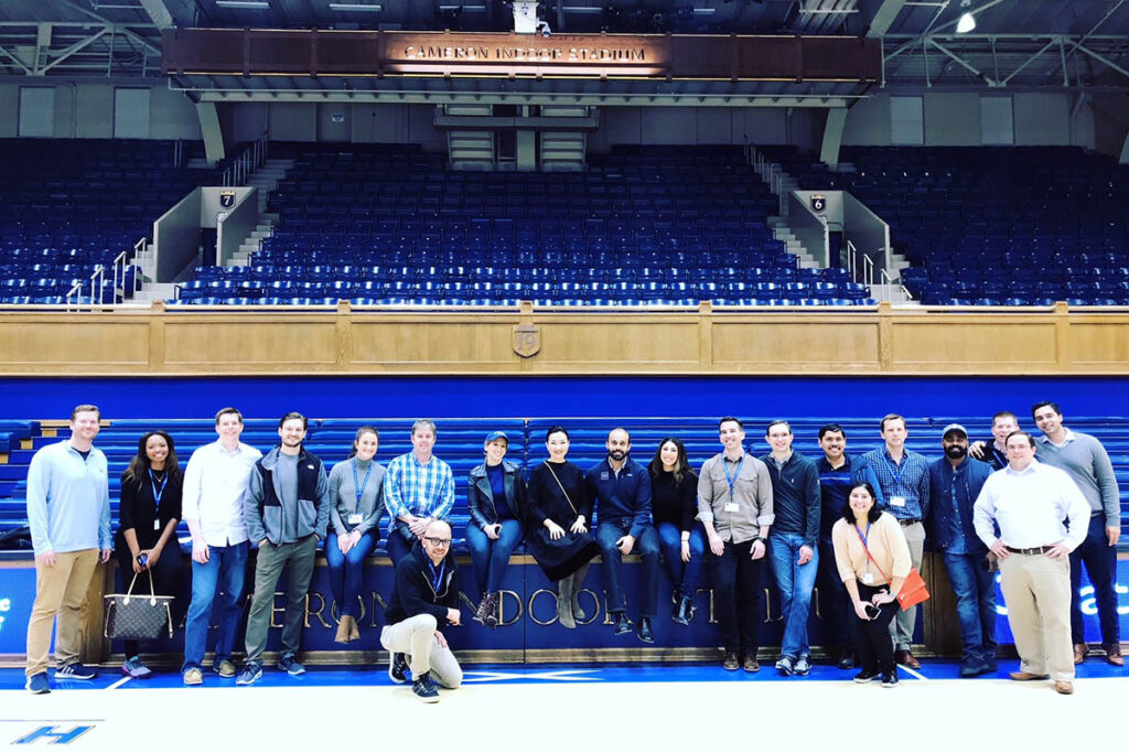 Assel and a dozen Duke Fuqua classmates posing for a photo in Cameron Indoor Stadium
