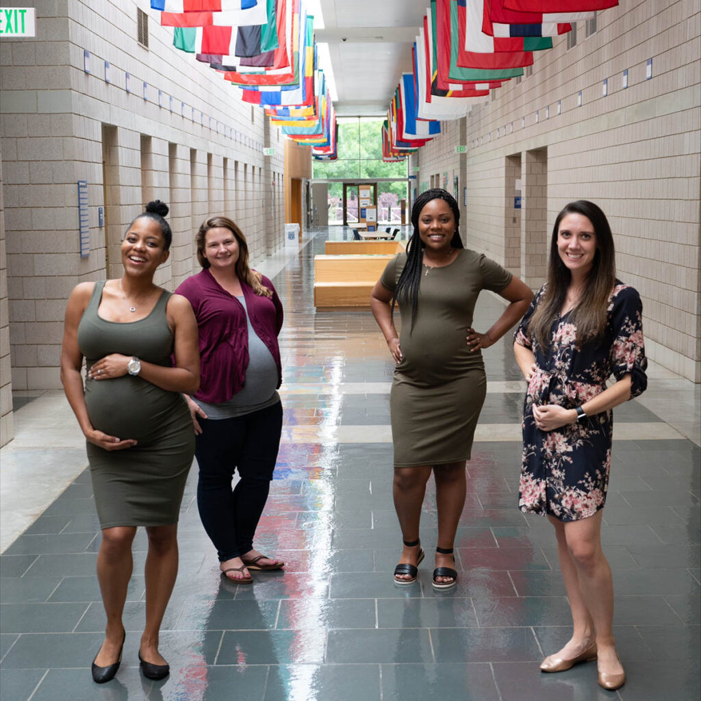 Zakiya pregnant in Fuqua's hallway with 3 other expecting moms from her cohort