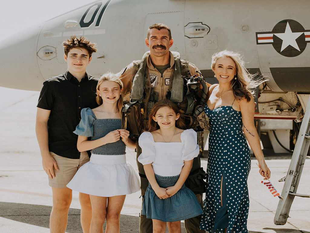 Tim Miller. a student in the Weekend Executive MBA program at Duke University's Fuqua School of Business, with his family, standing in front of a military aircraft