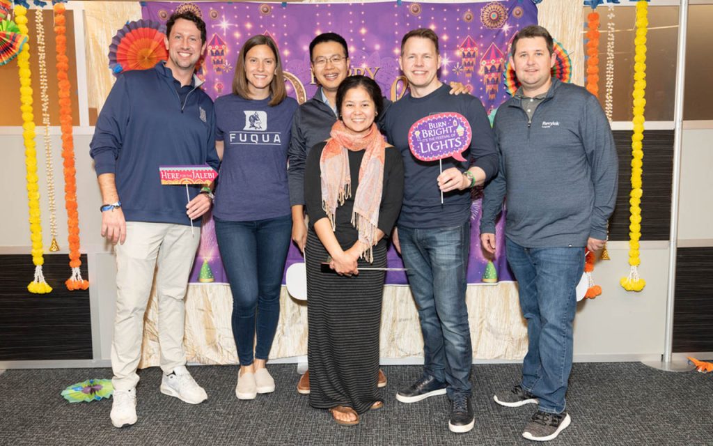 Mary Dohrmann and five of her Weekend Executive MBA classmates standing together, holding photo props