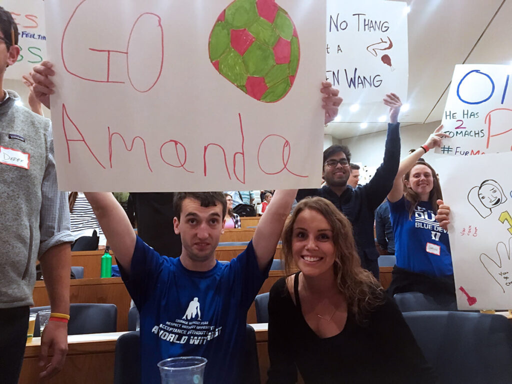 Stephanie and a Special Olympian holding up a sign at the MBA games fundraiser