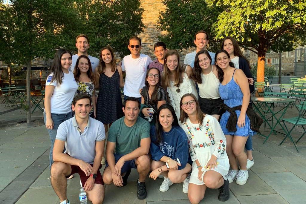 more than a dozen students including several from Fuqua's Latin American Student Association along with Duke undergrads pose for a photo on Duke's campus