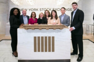 Eight people standing behind a desk at the New York Stock Exchange; D&I at Fuqua
