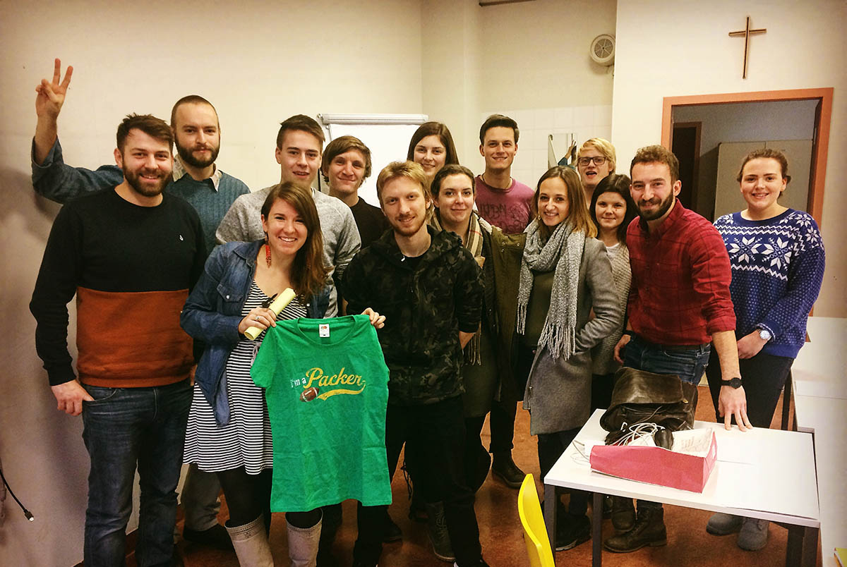 A group of people, with one person holding up a green t-shirt; language of business