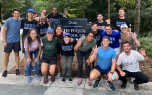 Students pose in front of Fuqua School of Business sign on Duke University's campus