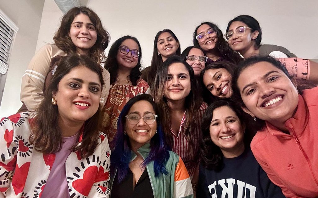 Vertika Srivasta stands front-left, appearing in a selfie-style photo with 10 other Daytime MBA students in the Association for Women in Business (AWIB) and INDUS