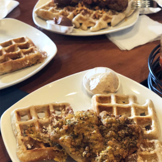 plates of waffles, one of which is topped with fried chicken, from Dame's one of Lily's brunch recommendations