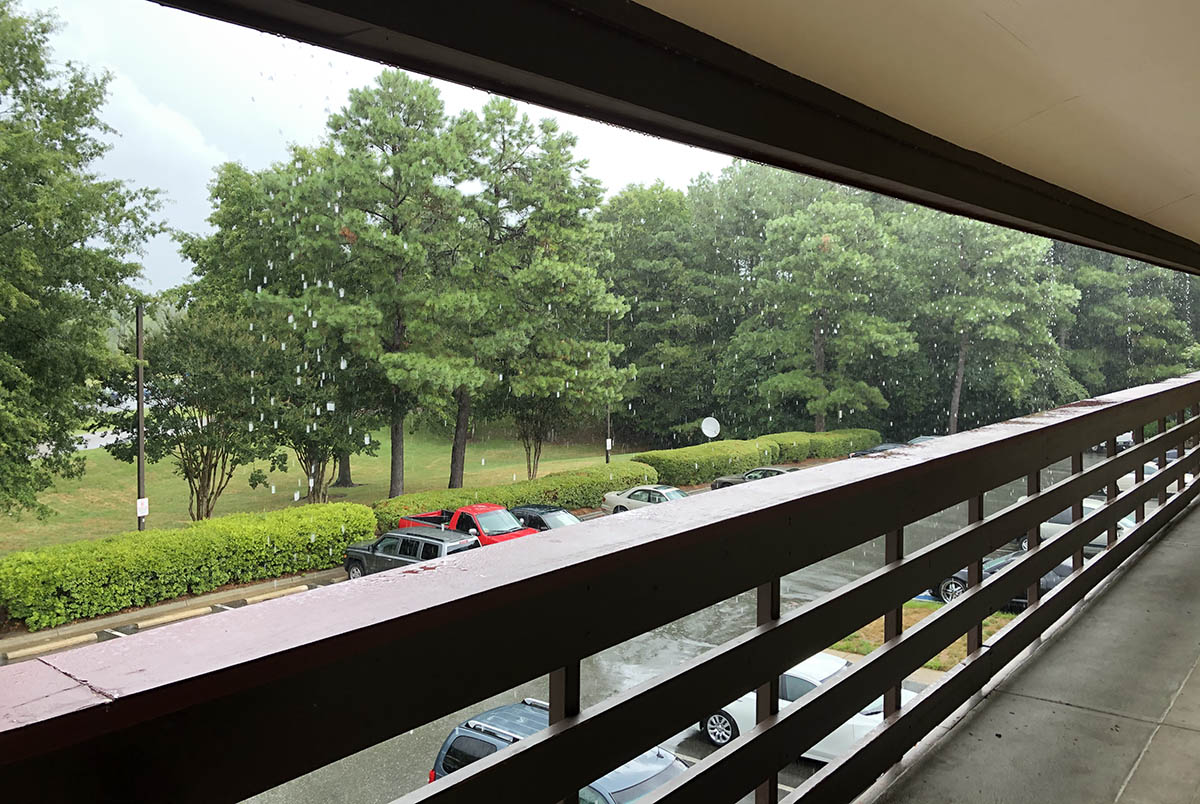 The view outside of a hotel room with rain falling and cars parked; Journey to Fuqua