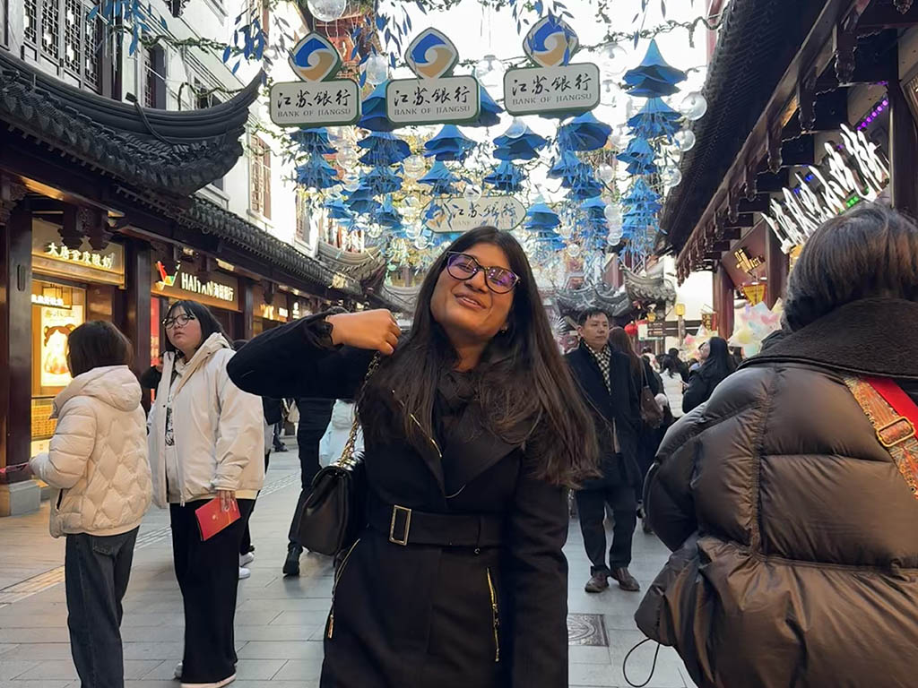 Ashima Garg, an MMS: DKU student at Duke University's Fuqua School of Business, standing front of a busy walkway with paper lanterns overhead