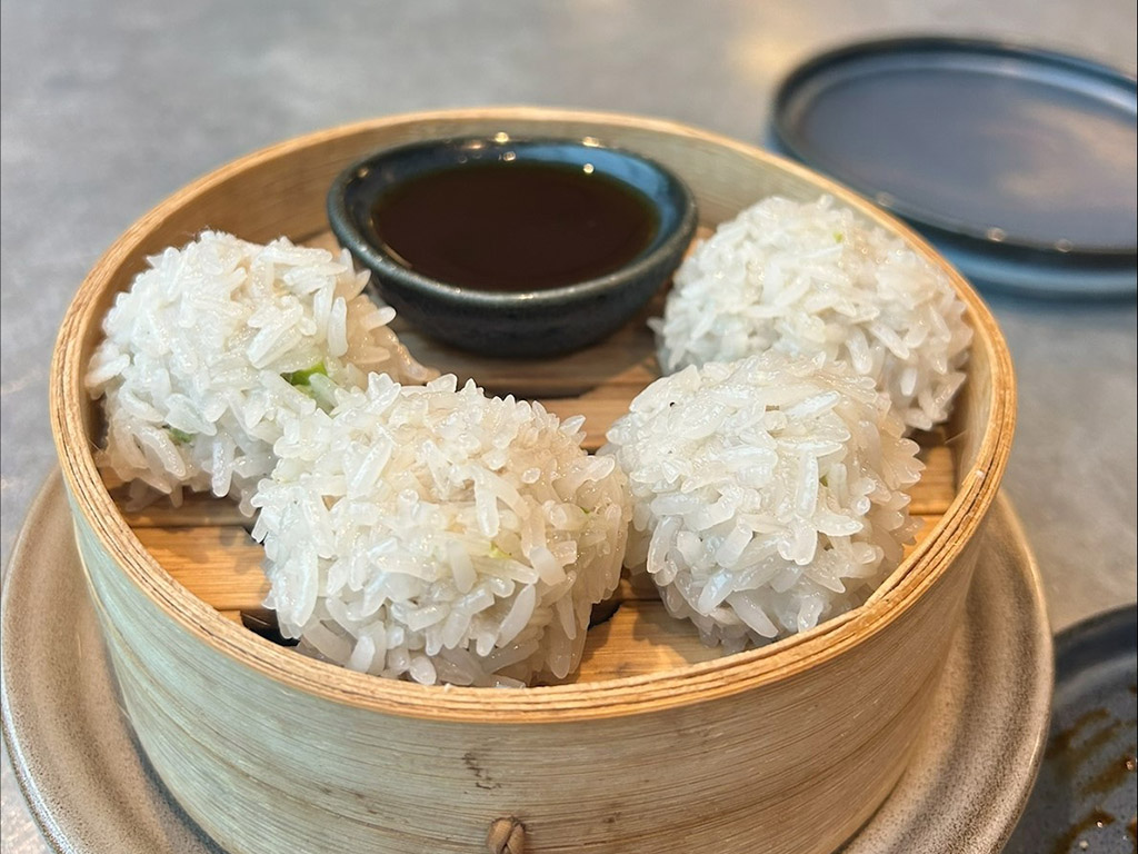 A minimalist dining table features a gourmet dish served in a steamer box
