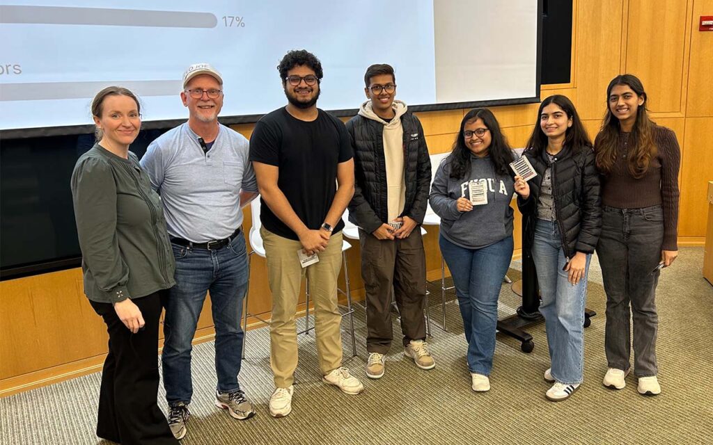 Aratrika Pal, a student in the MMS: Foundations of Business program, with her 4 teammates and staff overseeing the Fuqua's Specialty Masters Case Competition in a classroom at Duke University's Fuqua School of Business