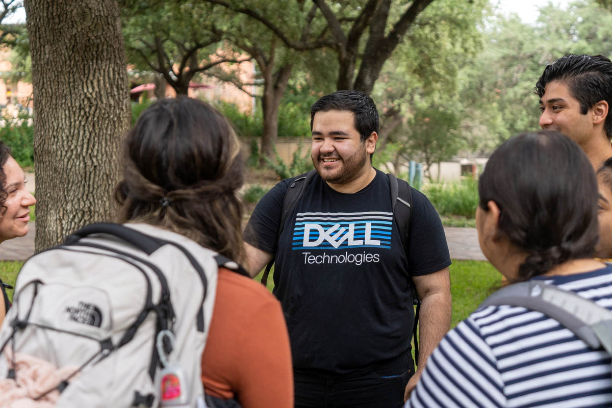 Thomás in a Dell shirt, where he got his first job in tech, talking to a small group of people