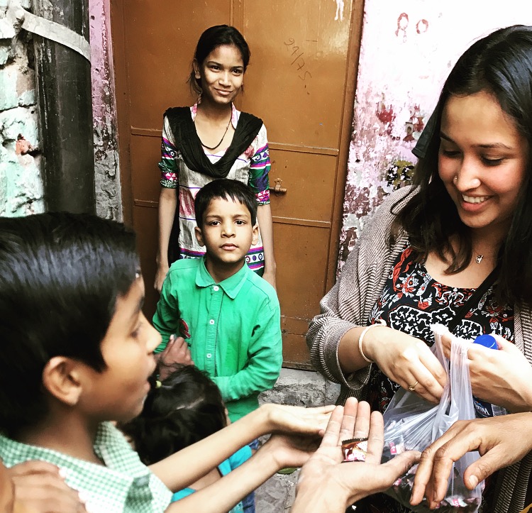 a student passes out goodies to kids in the slums of India during a social impact club outing
