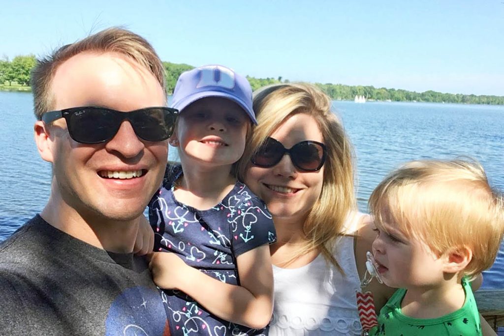 Jamie, his wife and two small kids posing for a selfie at a lake; family life