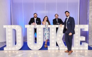 Drew Rotolo and three others stand by a lighted set of letters spelling "Duke." They are in formal attire.