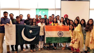 Two dozen students pose behind Indian and Pakistani flags, symbolic of student diversity at Fuqua