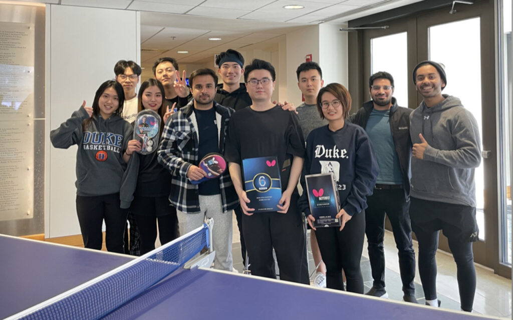 Winston Zhong and ten other students participate in the finance track ping pong tournment and take group photo in the Fox Center at Duke University's Fuqua School of Business