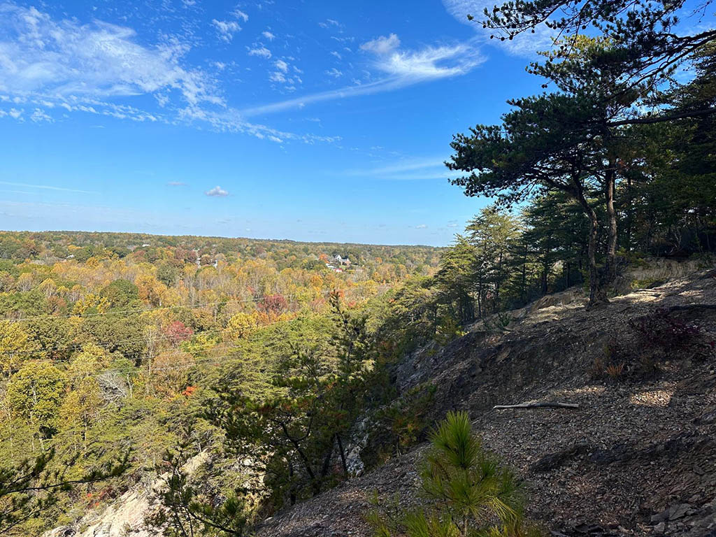 View from Occoneechee Mountain, forest of trees and bright blue, mostly clear sky