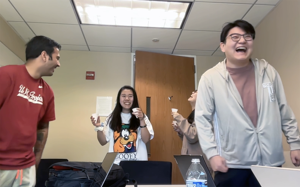 Betty Sun and two of her MQM capstone teammates laughing and holding cups in a Fuqua team work room