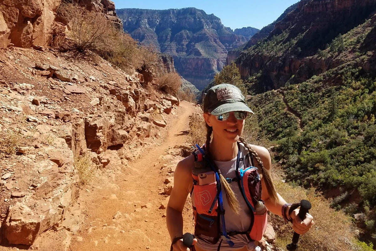 A woman wearing glasses, a hat and holding walking sticks in a rocky area; Ultrarunning and an MBA