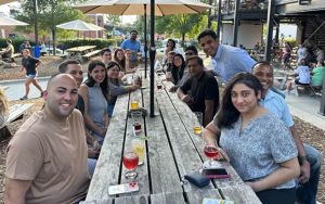 Jonathan Jean-Pierre and about 12 of his Fuqua classmates sitting at a long picnic table outside Durham brewery Ponysaurus