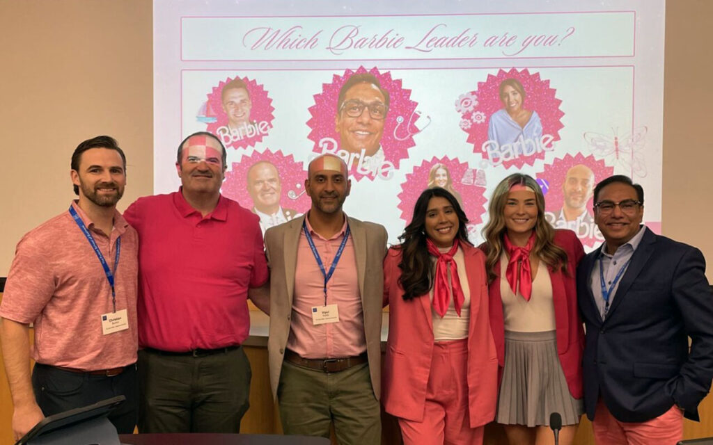Ana Zinn and three of her classmates stand at the front of a classroom and a presentation screen at Duke University's Fuqua School of Business